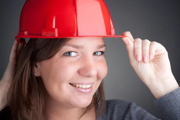 Portrait of young architect wearing red hardhat, looking at camera — Stock Photo, Image