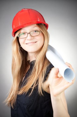 Young woman in helmet with blueprint, with grey background