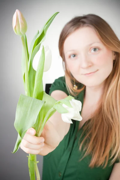 Menina loira nova com tulipas, com fundo cinza — Fotografia de Stock