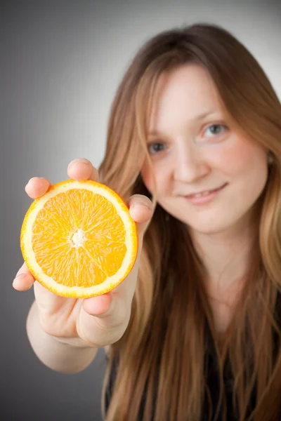 Beautiful blond girl showing a half orange — Stock Photo, Image