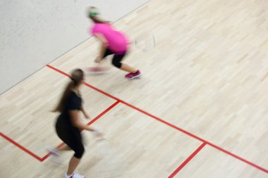 İki kadın squash oyuncular bir squash kortu (hareket bulanık görüntü; renk tonlu görüntü hızlı eylem içinde)