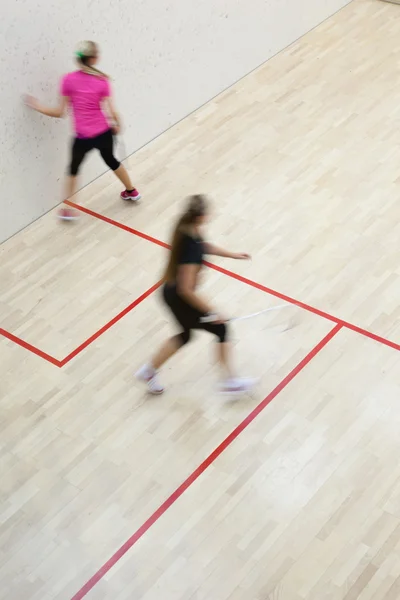 在上一个壁球 运动模糊的图像 定了调子的彩色图像的快速行动的两个女性壁球球员 — 图库照片