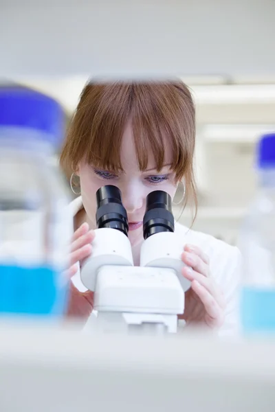 Investigadora bastante femenina usando un microscopio en un laboratorio — Foto de Stock