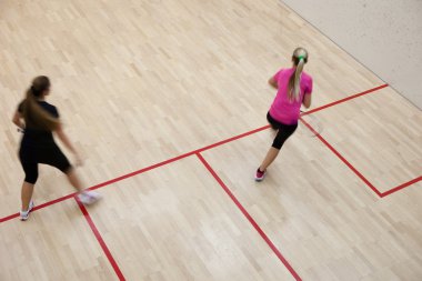 Two female squash players in fast action on a squash court (moti clipart