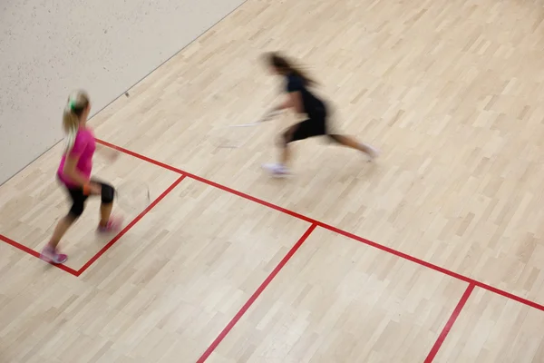 İki kadın squash oyuncular bir squash kortu (moti hızlı eylem içinde — Stok fotoğraf