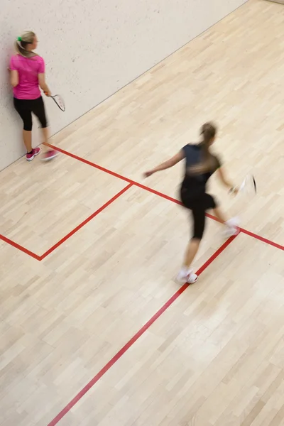 Zwei Squashspielerinnen in schneller Aktion auf einem Squash-Court (moti — Stockfoto