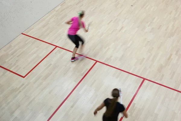 Duas jogadoras de squash feminino em ação rápida em uma quadra de squash (moti — Fotografia de Stock