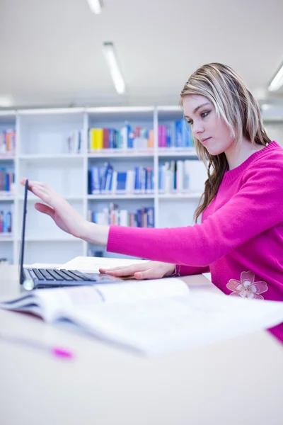 I biblioteket - vacker, kvinnlig student med laptop och böcker wo — Stockfoto