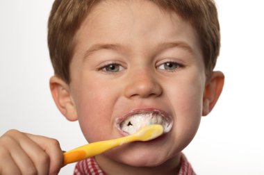 Cute young boy brushing teeth with positive expression clipart