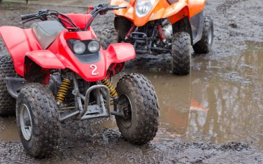 Two junior quad bikes in the mud ready for action clipart