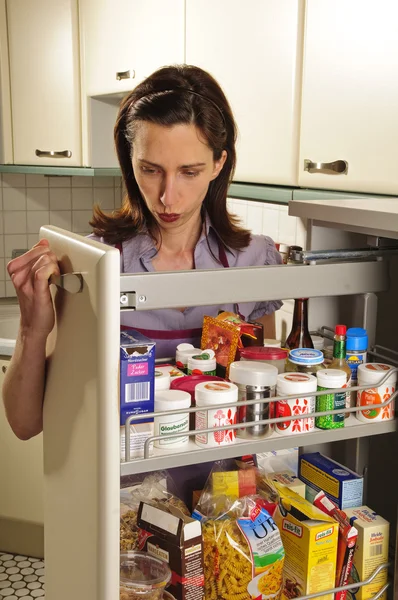Hospodyně v její kuchyni s lékárníkem kabinet — Stock fotografie