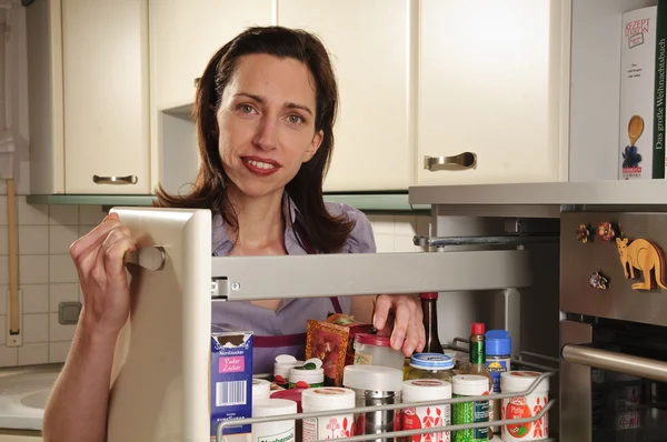Hospodyně v její kuchyni s lékárníkem kabinet — Stock fotografie