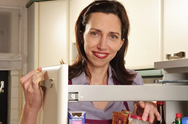 Femme au foyer dans sa cuisine avec armoire apothicaire — Photo