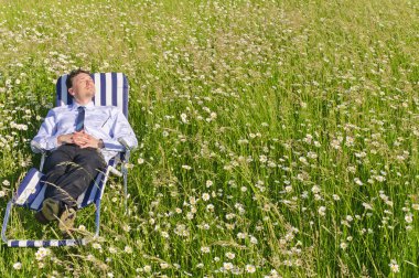 Businessman in suit is on a flowery meadow and relaxed clipart