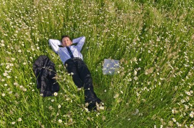 Businessman in suit is on a flowery meadow and relaxed clipart