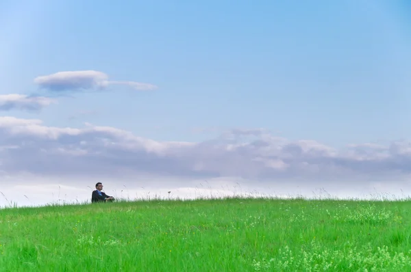Businessman Suit Sitting Meadow Looks Distance Front Clouds — Stock Photo, Image