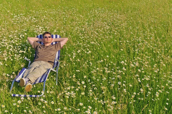 在草地上放松在甲板椅子上的男人 — 图库照片