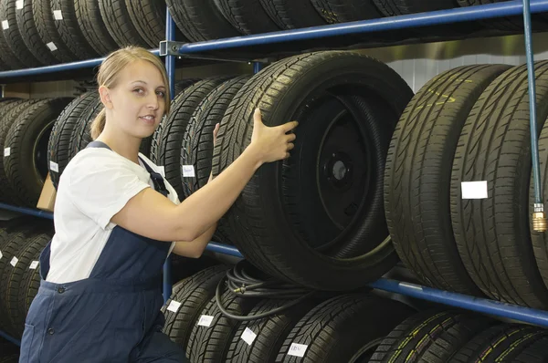 Female car mechanic with tire Stockfoto