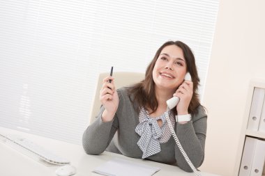 telefonda ofisinde çalışan genç iş kadını gülümseyen