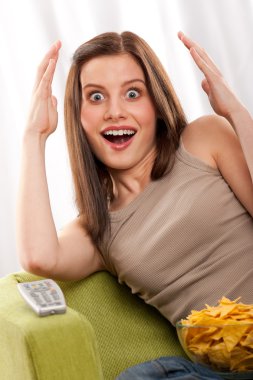 Young brown hair woman surprised by watchnig television clipart