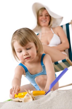 Mother with child playing with beach toys on sand clipart