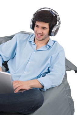 genç işadamı relax müzik ve fasulye çanta beyaz zemin üzerine oturan laptop ile