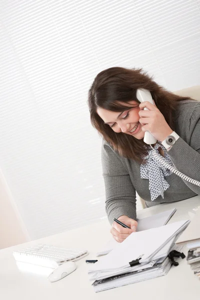 Lachende jonge zakenvrouw op telefoon op kantoor — Stockfoto