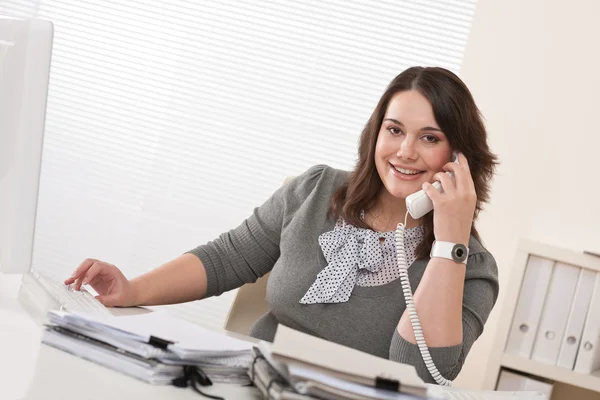 オフィスで電話に取り組んでいる若い女性の笑みを浮かべてください — ストック写真