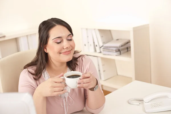 Молодая деловая женщина наслаждается кофе в современном офисе — стоковое фото