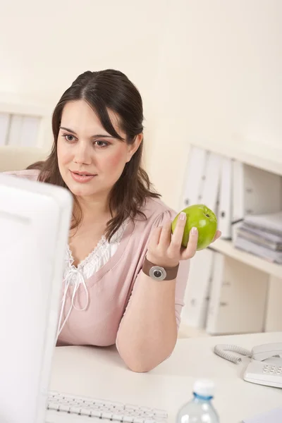 Jeune femme d'affaires heureuse tenant pomme au bureau — Photo