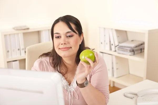 Jovem empresária feliz segurando maçã no escritório — Fotografia de Stock
