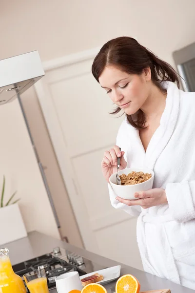 穿着浴衣健康谷物早餐吃在厨房里快乐的女人 — 图库照片
