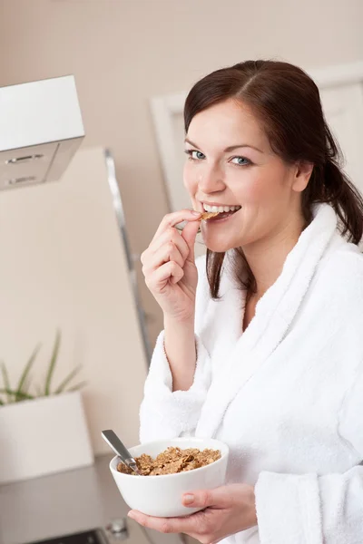 Szczęśliwa kobieta jedzenie zbóż śniadanie w kuchni — Zdjęcie stockowe
