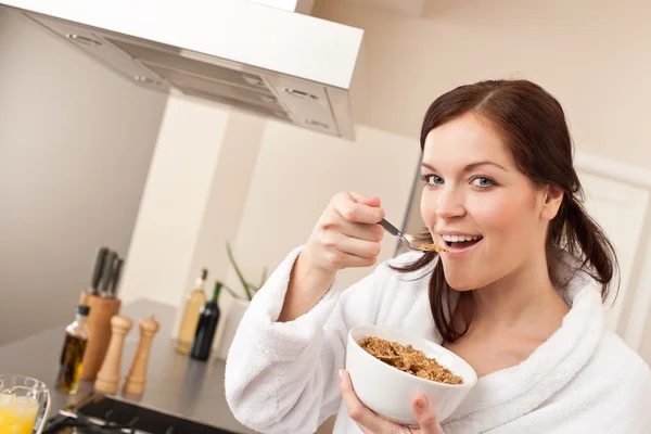Mulher feliz comendo cereais para o café da manhã na cozinha — Fotografia de Stock
