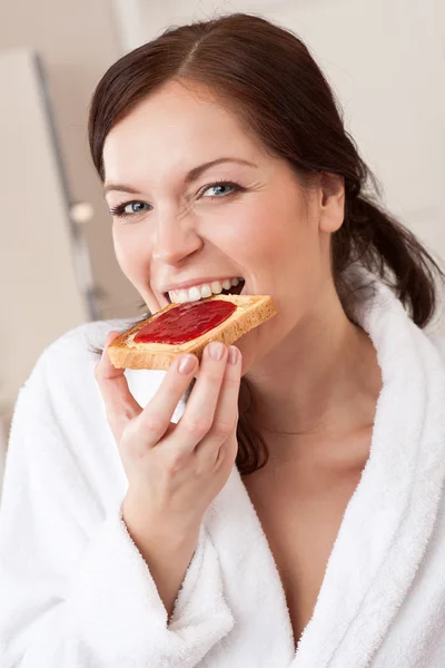 Young woman eating toast for breakfast in kitchen — Stock Photo, Image