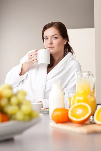 Genç kadın mutfakta kahve ve kahvaltı keyfi — Stok fotoğraf