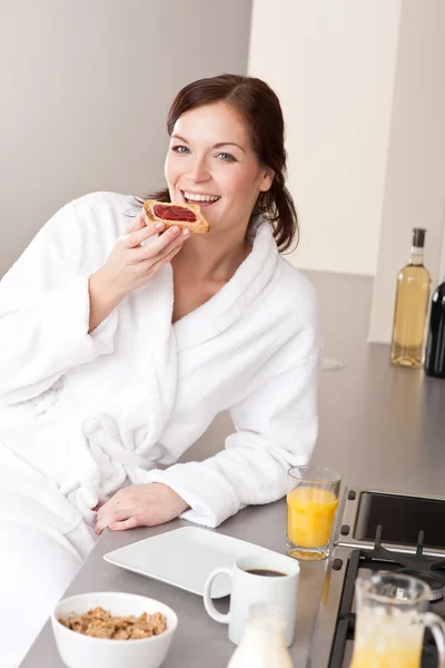 Jovem mulher comendo torrada no café da manhã na cozinha — Fotografia de Stock