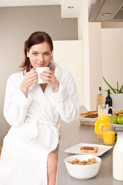 Mujer joven disfrutando de café y desayuno en la cocina —  Fotos de Stock