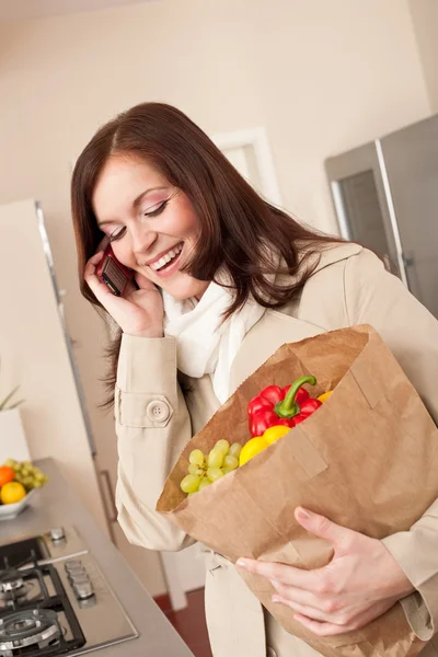 Lachende vrouw met mobiele telefoon bedrijf boodschappentas — Stockfoto