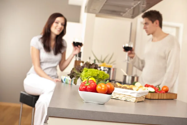 在厨房里喝红酒对年轻夫妇重点配菜碗 — 图库照片