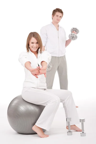 Молода пара з вагами і фітнес-кулькою на білому — стокове фото