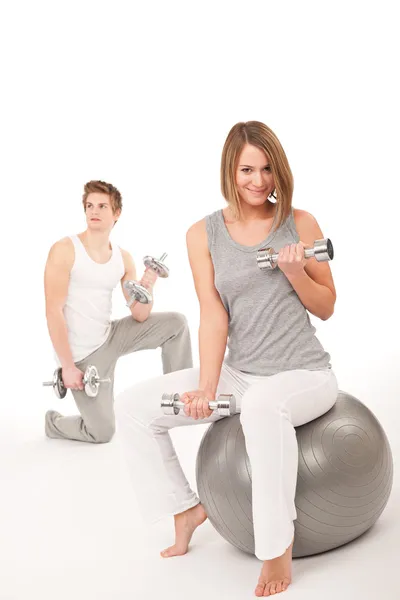 Young couple with weights and fitness ball on white — Stock Photo, Image