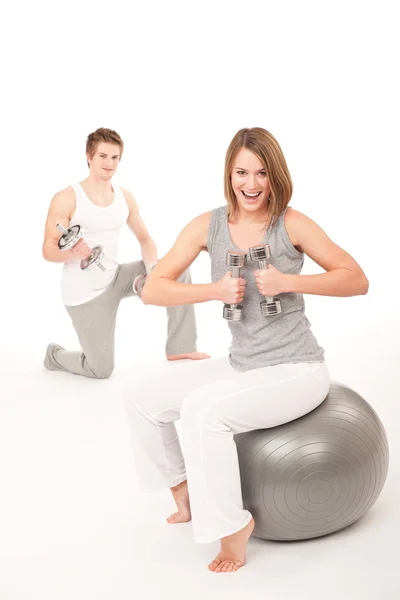 Mladý pár s váhami a fitness míč na bílém pozadí — Stock fotografie