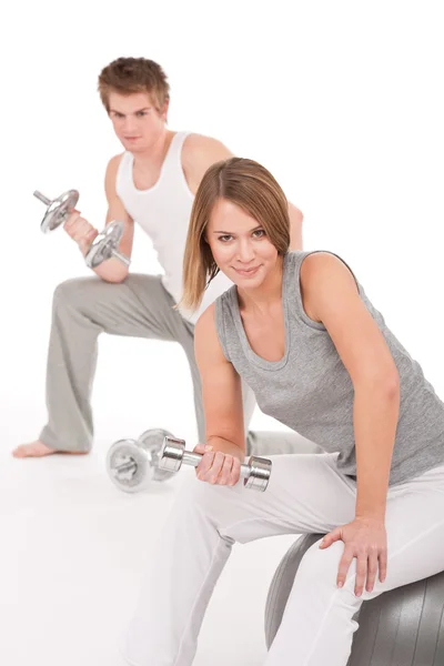 Mladý pár s váhami a fitness míč na bílém pozadí — Stock fotografie
