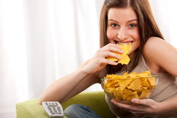 テレビの前でポテトチップスを食べる若い女性 — ストック写真