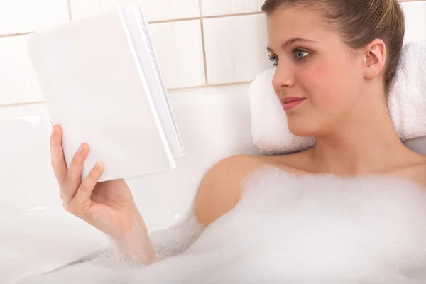 Body care serien - ung kvinna läser bok i badkaret — Stockfoto