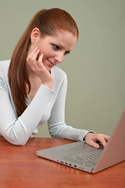 Dizüstü bilgisayar ile ofisinde çalışan uzun kızıl saçlı kadın — Stok fotoğraf