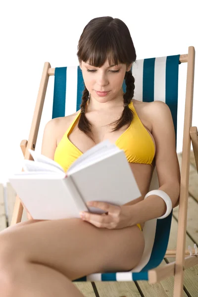 ビーチ ビキニで若い女性の本のデッキチェアで日光浴を楽しみながらリラックスします — ストック写真