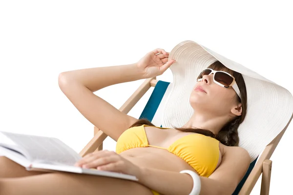 ビーチ ビキニと帽子で若い女性本のデッキチェアで日光浴とリラックスします — ストック写真