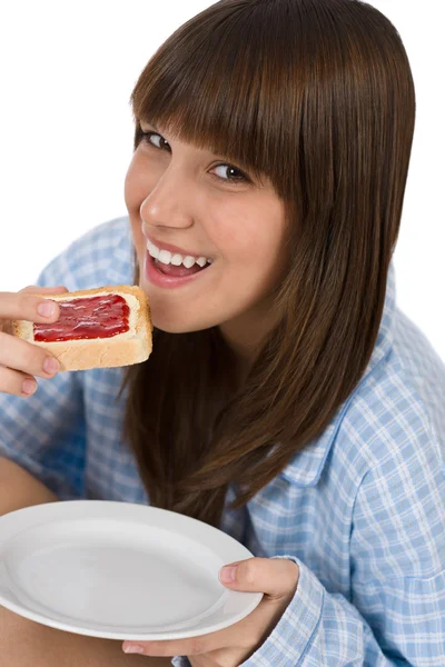 Happy teenager in pajamas eating healthy toast — Stock Photo, Image